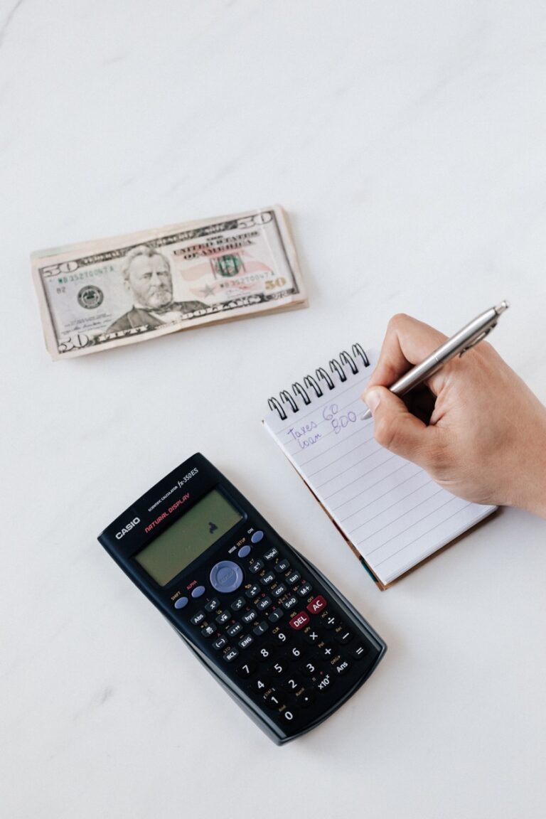 A person jotting down calculations on a notepad with a calculator and pen, implementing a cost control strategy to manage their marketing budget and boost profits.