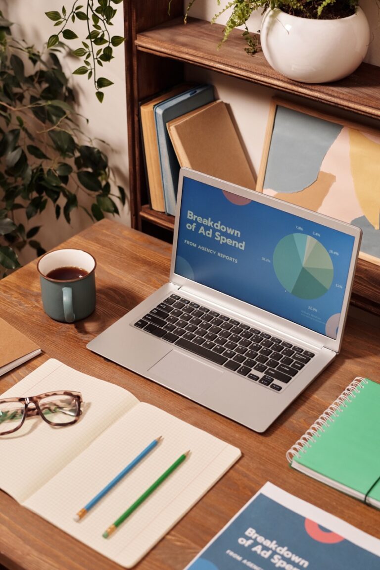 Calculating the Power of ROAS: A laptop on a wooden desk with a plant on it.