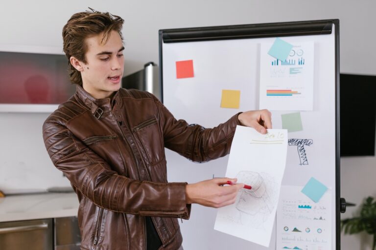 A man is analyzing marketing data while wearing a leather jacket and drawing on a whiteboard.